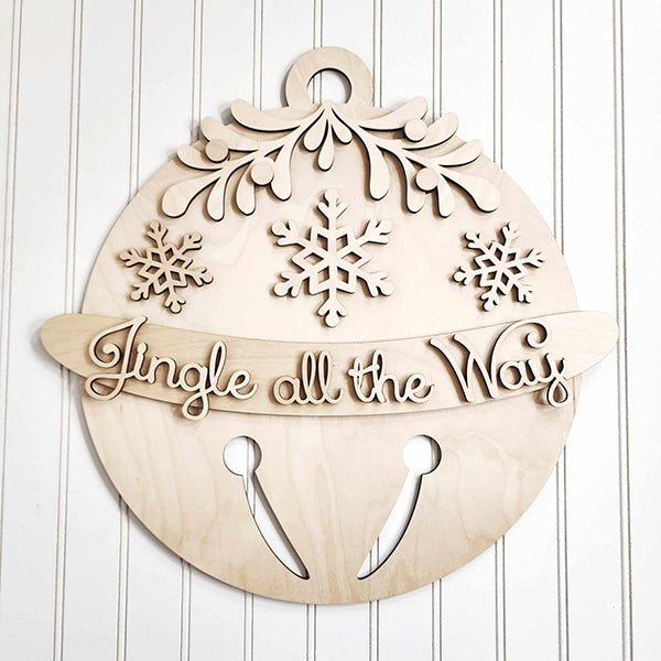 Introducing the Jingle Bell Door Hanger from Janet's Craft Corner: a wooden DIY craft kit designed as a holiday ornament adorned with snowflakes and greenery. It showcases the phrase "Jingle all the Way" in cursive, complete with a cut-out jingle bell pattern at the bottom, making it an ideal addition to enhance your home décor.