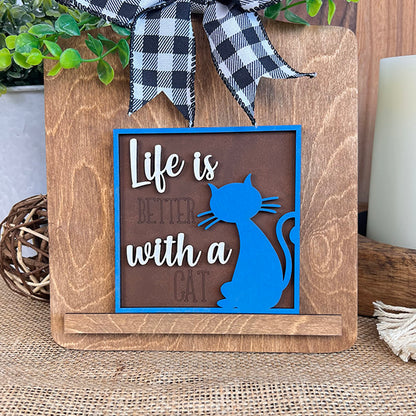 Janet's Craft Corner Cat Swappable Squares features a wooden sign with a blue cat silhouette, “Life is better with a cat,” wood cut-outs, black and white ribbon, greenery—perfect DIY rustic home decor.
