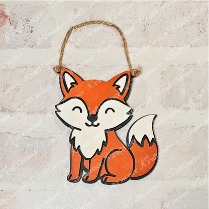 The Little Fox Kids Pop-Out from Janet's Craft Corner features a cute, cartoon orange fox with a white belly, face, and tail tip. It hangs by a brown string and is perfect for holiday décor or the Trim a Tree Kids Pop-Out Kit.