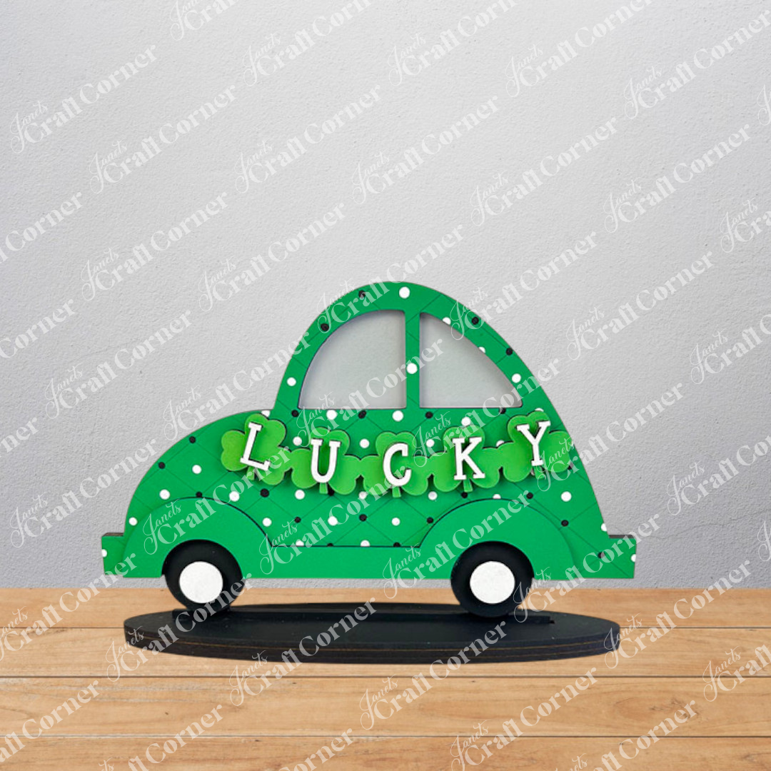 The Lucky St. Patrick's Volkswagen Shelf Sitter by Janet's Craft Corner showcases a decorative green car cutout with a polka dot pattern and the word "LUCKY" across the center, embellished with clover shapes. Ideal for St. Patrick's Day decor, this charming car sits gracefully on a black base.