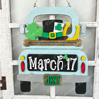 The "March 17 Interchangeable Insert" from Janet's Craft Corner is a decorative piece designed to resemble the back of a truck, perfect for celebrating St. Patrick's Day. It features symbols like a shamrock, leprechaun hat, and horseshoe, along with the date "March 17." With "LUCKY" displayed on the license plate, this DIY home decor kit makes an ideal piece of interchangeable home decor against a white, rustic background.