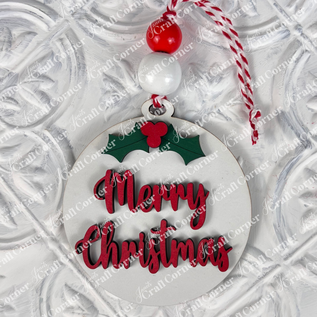 Introducing the Round Christmas Ornaments from Janet's Craft Corner, featuring a charming design with "Merry Christmas" in vibrant red letters. These ornaments include a lovely holly decoration, accented by a decorative red and white bead, and are suspended from a matching red and white string against a festive white background—ideal for enhancing your DIY Decoration Kits this holiday season.