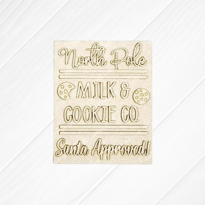 The North Pole Switchable Farmhouse Sign by Janet's Craft Corner features “North Pole Milk & Cookie Co. Santa Approved!” with cookie illustrations on a textured background—perfect for festive DIY holiday home decor.