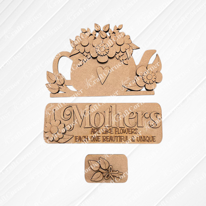The "Mothers Interchangeable Insert" DIY home decor kit by Janet's Craft Corner includes a wooden teapot cutout adorned with flowers and a heart, along with a sign that says, "Mothers are like flowers, each one beautiful & unique." This delightful craft kit features interchangeable inserts and showcases a small flower bouquet design set against an embossed burlap-textured background.