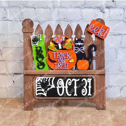 An enchanting Halloween-themed display depicts a garden fence adorned with vibrant signs that say "Boo," "Trick or Treat," and "Oct 31." This DIY craft kit from Janet's Craft Corner, named the Oct 31 Interchangeable Insert, features hand-painted elements including candies, a black cat with a pumpkin, and other festive decorations—ideal for creating versatile home decor.