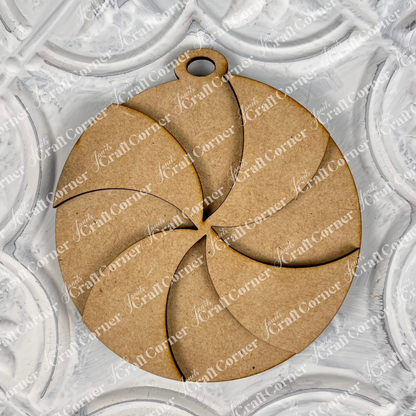A round ornament from Janet's Craft Corner, featuring a swirl pattern, rests on an embossed white surface with a floral design. Ideal for your festive decorations, this Christmas ornament includes a small loop at the top for easy hanging.