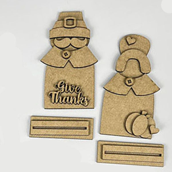 Introducing the "Give Thanks/Thanksgiving Tiered Tray Kit" from Janet's Craft Corner: this charming set includes wooden cutouts of a pilgrim couple with "Give Thanks" inscribed on one, complete with small stand bases. Ideal for home décor or as an accent piece for a tiered tray, these figures are stylized with hats and collars and come accompanied by an apple and pumpkin cutout.