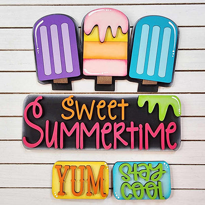 The Popsicle Interchangeable Insert from Janet's Craft Corner, a DIY home decor kit, features colorful popsicle decorations and includes a sign with "sweet summertime" in pink letters. Below it, two smaller signs proclaim "YUM" in orange and "STAY COOL" in green, all beautifully set against a white wooden surface to enhance this charming piece.