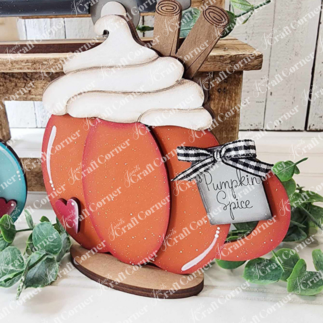 The Fall Harvest Mini Shelf Sitters DIY kit by Janet's Craft Corner, available in 9 seasonal designs, features cozy pumpkin-themed decor perfect for autumn displays on rustic surfaces surrounded by greenery.