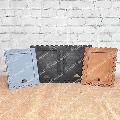 Janet's Craft Corner Single Scallop Trim Farmhouse Frames in blue, black, and brown stand upright on burlap before a white brick wall—ideal for interchangeable displays or creative DIY craft projects.