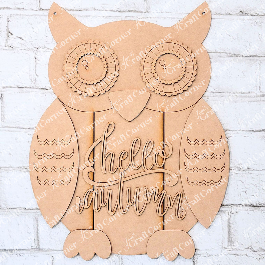 The Shiplap Owl Door Hanger DIY home decor kit from Janet's Craft Corner is a delightful project featuring detailed designs on the owl's eyes and wings. The center of the hanger displays the message "hello autumn," beautifully contrasted against a white brick background.