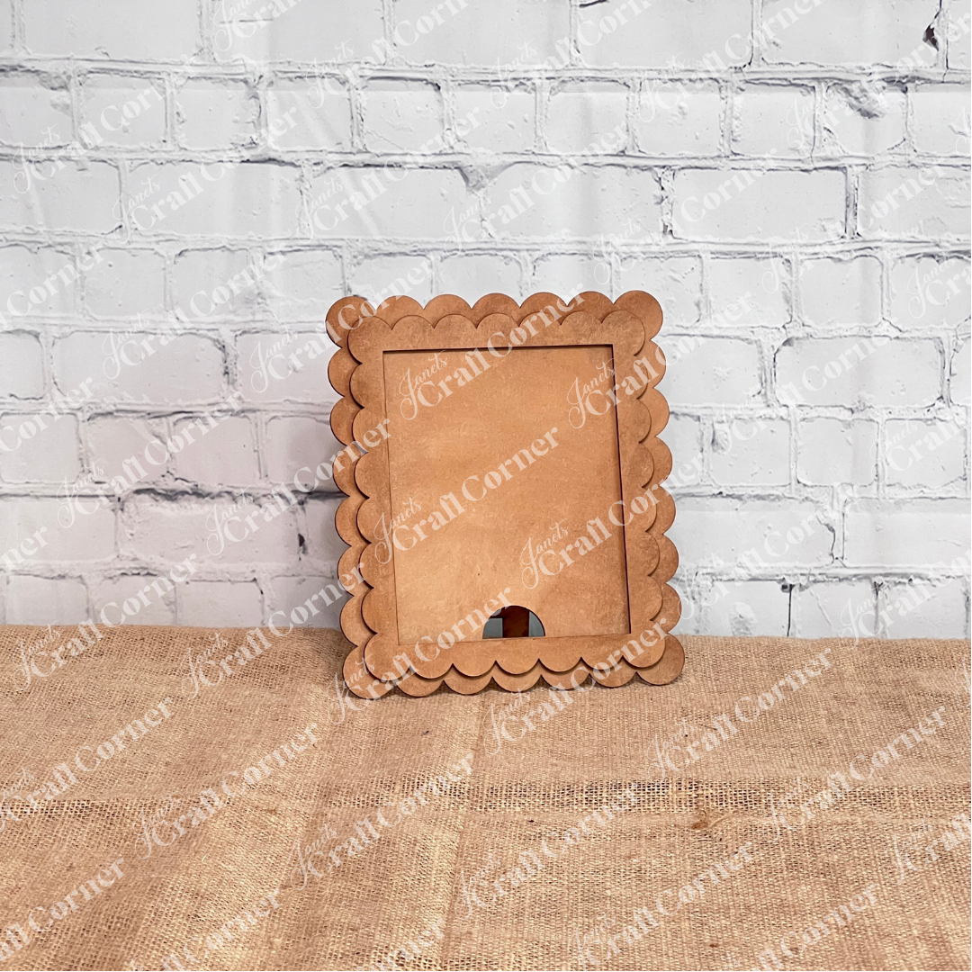 Janet's Craft Corner's Single Scallop Trim Farmhouse Frame with an unfinished scalloped edge stands upright on burlap, ideal for DIY projects, and is set against a white brick wall.