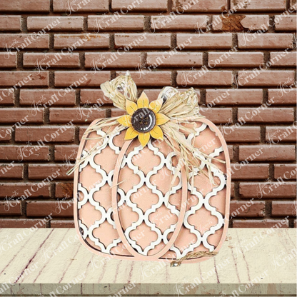 The Fall Harvest Mini Shelf Sitters DIY craft kit by Janet's Craft Corner features a beige and white lattice pumpkin with sunflower and raffia bow—perfect autumn decor for your home. Set of 1. Displayed in front of a red brick wall and light wood surface.