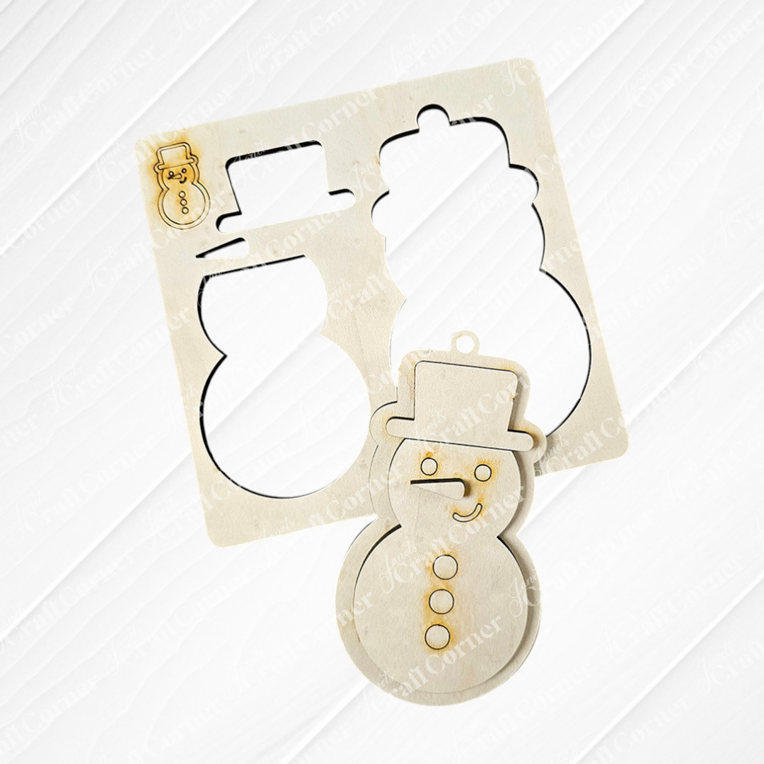 A wooden cutout showcasing a snowman shape with a top hat and scarf sits on a wooden table, accompanied by the stencil used to craft its snowman outline. Ideal for enthusiasts of Personalized Home Décor or those looking to add charm to DIY Craft Kit projects from Janet's Craft Corner, such as their "Sugar Cookie Ornaments - Set of 3.