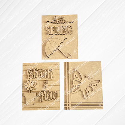 Janet's Craft Corner Spring Switchable Farmhouse Signs DIY Kit includes three brown cut-out wooden plaques: "hello SPRING" with an umbrella, "bloom & grow" with a flower pot, and a butterfly—perfect for spring tiered tray decor.