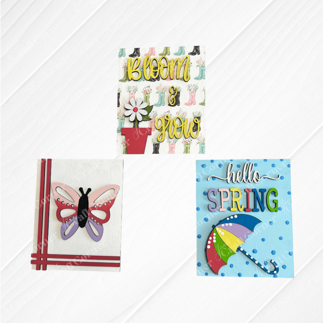 Decorate for spring with Janet's Craft Corner Spring Switchable Farmhouse Signs DIY Decor Kit. Includes "Bloom & Grow" with potted flower, a 3D butterfly, and "Hello Spring" umbrella design—perfect for tiered trays or seasonal displays.