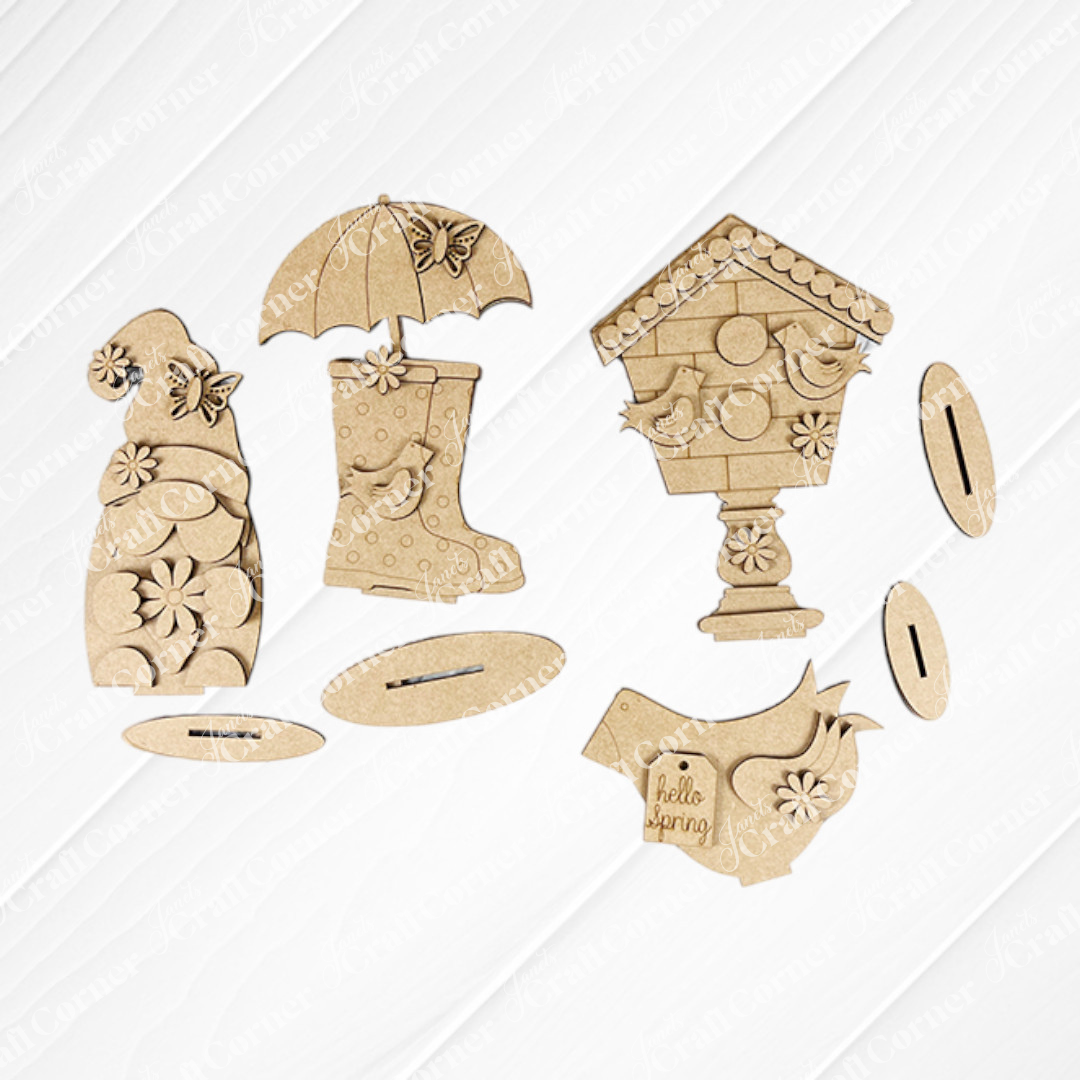 The Spring Mini Shelf Sitters by Janet's Craft Corner is a DIY decor kit including: a gnome with flowers, a rain boot with a butterfly, and birdhouses teeming with birds. "Hello spring" is etched on one bird. These pieces rest on textured surfaces above white tiles, perfect for your gnome décor collection.