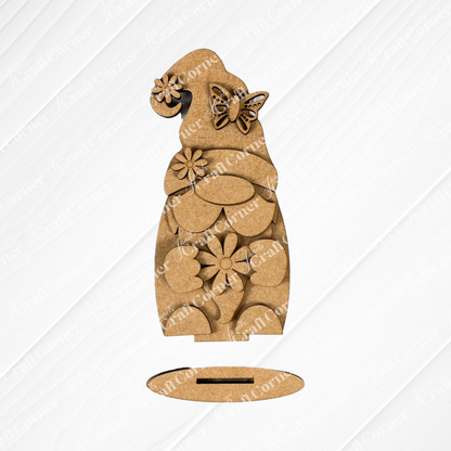 Introducing the Spring Standing Signs from Janet's Craft Corner: an enchanting wooden gnome cutout dressed with a butterfly adorning its hat and floral designs across its body, ideal for adding a touch of charm to your spring décor. Set on a white wooden background, this delightful piece features a slot base for stable home display.