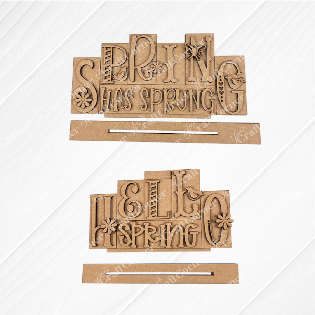 The Hello Spring Mini Word Blocks by Janet's Craft Corner are DIY seasonal home decor craft kits. Featuring the words "HELLO SPRING" or "SPRING HAS SPRUNG" with decorative lettering, flowers, and a birds on a rectangular base, it's perfect against textured white backgrounds for creative projects. Set of 1 included.