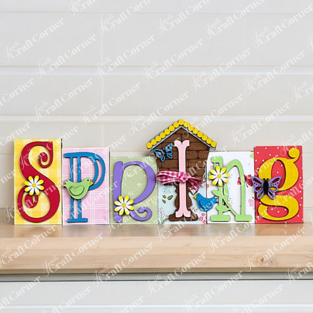 The "Spring Word Block" by Janet's Craft Corner is an ideal addition to home decor, showcasing vivid letters and lively designs of birds, flowers, butterflies, and a quaint house. Displayed against a brick wall on burlap, this delightful piece captures the imaginative charm of a DIY kit with its bright springtime essence.