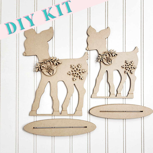 The Standing Deer Shelf Sitter DIY Home Decor Kit - Set of 2, from Janet's Craft Corner, includes two wooden deer cutouts adorned with hand-painted floral and snowflake designs. These delightful home decor pieces are beautifully showcased against a white panel background.