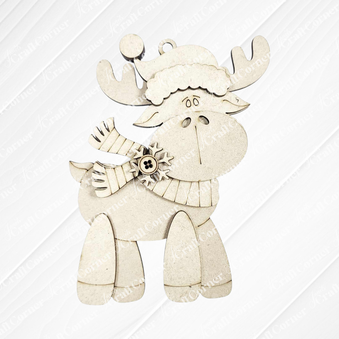 A cute cartoon reindeer in a hat and scarf holds a snowflake on a white textured background. Perfect for Janet's Craft Corner Forest Friends Ornaments DIY craft kits—choose from 5 adorable animal designs!.