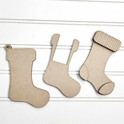 Three cardboard cutouts of Christmas stockings from Janet's Craft Corner are displayed on a white background. Each stocking in the DIY craft kit, Stocking Money Holder Ornament - Set of 1, features a unique design with variations like a hanging loop and textured top—ideal for holiday cash gifts.