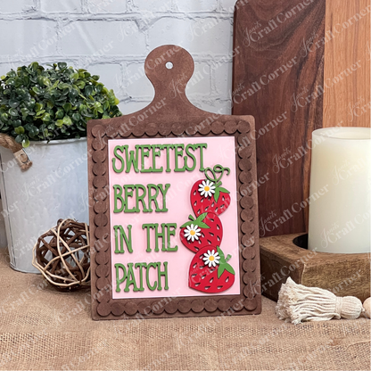 Janet's Craft Corner Bead Trim Breadboard Frame displays a "Sweetest Berry in the Patch" farmhouse sign with strawberries and daisies, styled on wood alongside a candle, greenery, and rustic ornaments. Set of 1 DIY home decor craft kit.