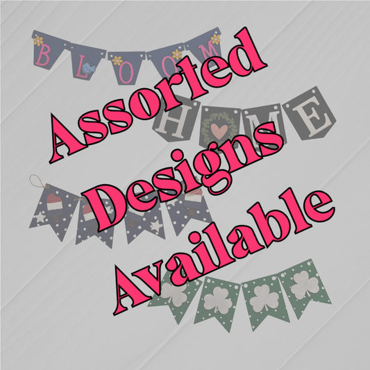 Janet's Craft Corner Tiered Tray Garlands in assorted designs like "BLOOM," "HOME," Santa hats, and shamrocks, shown on a light background. Bold pink text states: Assorted Designs Available.