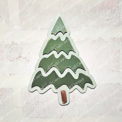 A wooden Christmas tree ornament from Janet's Craft Corner's Trim a Tree Kids Pop-Out Kit rests on a light textured background. The tree, perfect for personalizing holiday décor, features three green tiers with a small brown trunk at the bottom.