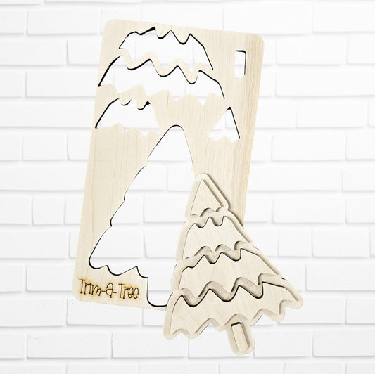 Experience the finest in holiday decor with Janet's Craft Corner's "Trim a Tree Kids Pop-Out Kit." This DIY craft kit features a wooden Christmas tree puzzle with a distinctive cut-out piece in front. The stylized tree showcases wavy branch patterns and an engraved "Trim-a-Tree" on its base. Set against a white brick wall, it serves as a charming accent for any festive setting.