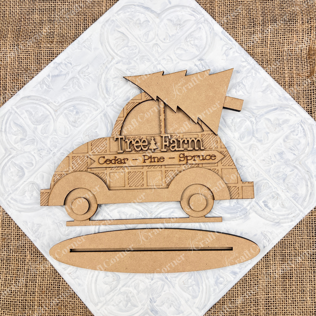 The "Tree Farm Volkswagen Shelf Sitter", a DIY home décor craft kit from Janet's Craft Corner, features a hand-painted wooden cutout of a vintage car carrying a Christmas tree. It is labeled "Tree Farm" with the words "Cedar - Pine - Spruce," making it an ideal piece for home decoration. Set against a textured background, this charming item adds a rustic touch to any space.