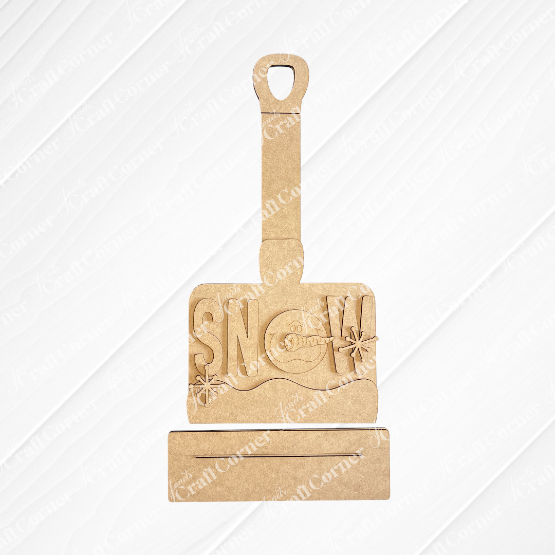 The Winter Snow Shovel Shelf Sitter DIY kit by Janet's Craft Corner features a gray shovel with “SNOW” cutouts and a snowman in the “O”—a charming winter décor piece for your home. Set of 1.