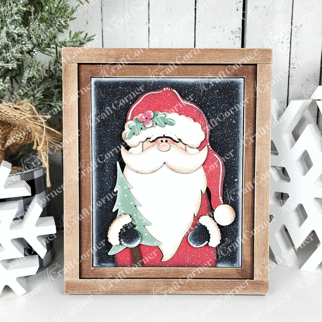 Janet's Craft Corner's North Pole Switchable Farmhouse Signs features Santa holding a green Christmas tree with snowy accents and pine branches—a festive DIY kit for seasonal home decor.