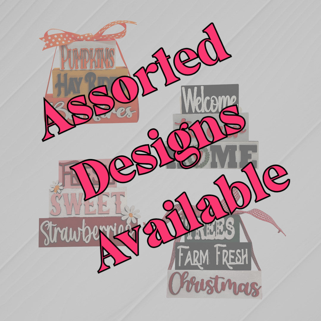 A graphic features four rustic farmhouse-style Word Stacks - Painted signs by Janet's Craft Corner with autumn and Christmas themes. Large pink text across the image reads, "Assorted Designs Available.