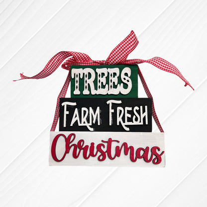 Janet's Craft Corner Word Stacks - Painted: three stacked blocks reading "TREES," "Farm Fresh," and "Christmas," tied with a red and white checked ribbon, displayed on a white wooden background.