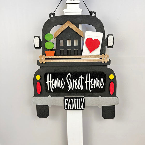 Using the Home Sweet Home Interchangeable Insert DIY home decor kit from Janet's Craft Corner, you can transform a decorative truck-shaped sign featuring "Home Sweet Home" and a "Family" license plate into a versatile home decor piece. The kit includes inserts with a house cutout, potted plant, envelope, and red heart to symbolize warmth and family.