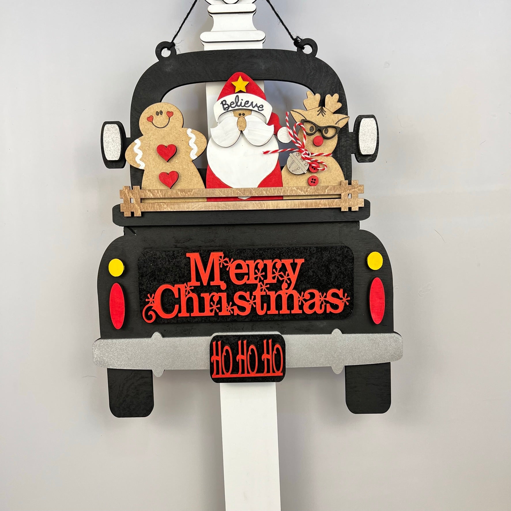 Decorative wooden Christmas sign by Janet's Craft Corner, featuring their Antique Truck Base DIY home decor kit. This delightful piece carries Santa, a gingerbread figure, and a reindeer with interchangeable inserts for customizable festive messages such as "Merry Christmas" and "Ho Ho Ho," complete with charming embellishments.