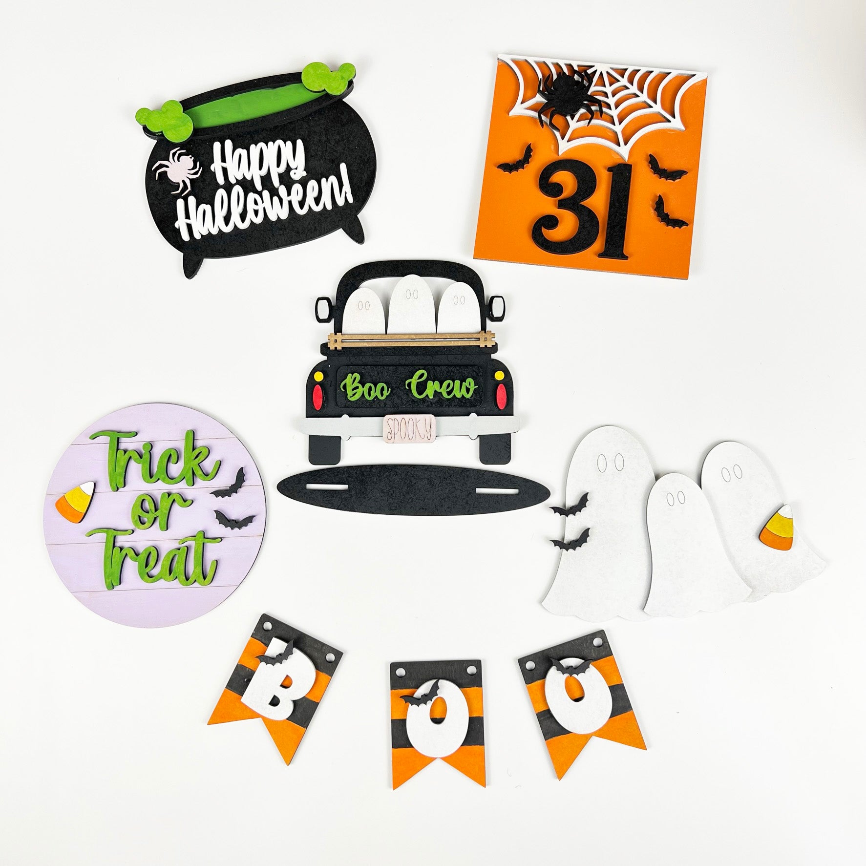 Janet's Craft Corner presents the Boo Crew Tiered Tray Kit, featuring Halloween-themed decorations like a cauldron with "Happy Halloween," a truck with ghosts labeled "Boo Crew," and banners displaying ghost, spider web, bats, "31," "Trick or Treat," and "BOO" in black, orange, and white. Ideal for your DIY Halloween decor project!