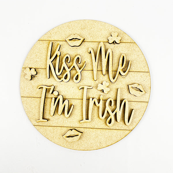 This delightful round wooden sign from Janet's Craft Corner is perfect for festive decorating. It features "Kiss Me I'm Irish" engraved in the center, surrounded by delicate images of lips and shamrocks. It's ideal for adding a touch of whimsy to your home décor or as part of the Lucky St Patricks Tiered Tray Kit.