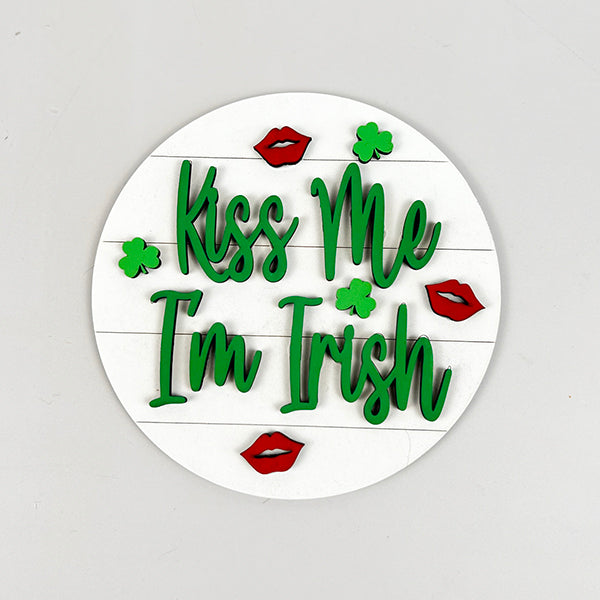 This round sticker, ideal for adding a festive touch or incorporating into Janet's Craft Corner's Lucky St Patricks Tiered Tray Kit, showcases the phrase "Kiss Me I'm Irish" in green on a white background embellished with red lip prints and green shamrocks.