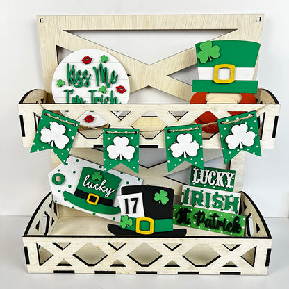 A wooden display stacked with St. Patrick's Day-themed decorations, including shamrocks, leprechaun hats, and signs reading "Kiss Me I'm Irish," "Lucky," and "Irish." Enhance your festive decorating with the Lucky St Patricks Tiered Tray Kit from Janet's Craft Corner, featuring a green and white banner adorned with shamrocks.