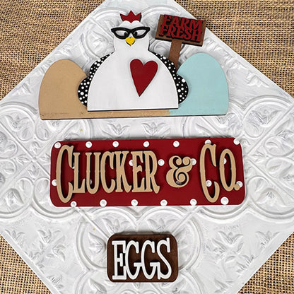 A textured decorative sign set includes a cartoon chicken motif wearing glasses and a "Farm Fresh" sign, accompanied by the illuminated red Clucker & Co. sign by Janet's Craft Corner, which adds rustic charm alongside a brown "Eggs" sign, ideal for interchangeable craft inserts.