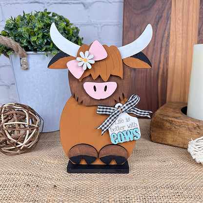 The Farm Standing Shelf Sitter by Janet's Craft Corner is an adorable wooden cow figurine adorned with a pink bow and a flower on its head, perfect for adding a rustic touch to any space. Featuring a tag that reads, "Life is better with cows," it complements charming farmhouse decor beautifully with its delightful decorative elements.